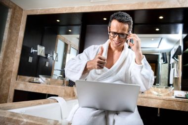 Businessman in bathrobe working with devices clipart