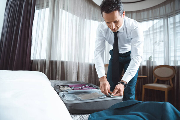 Businessman unpacking suitcase