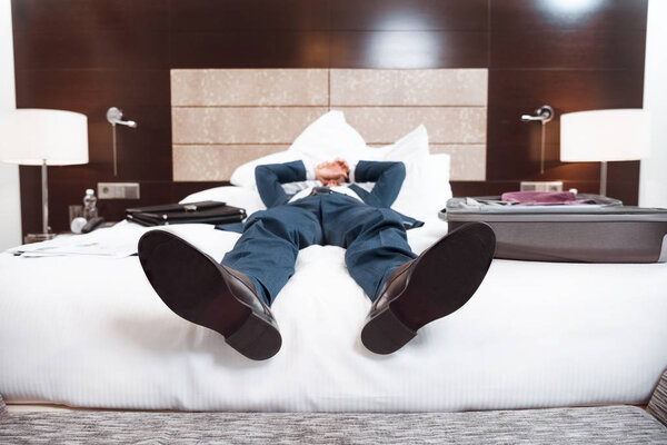 Exhausted businessman lying on bed