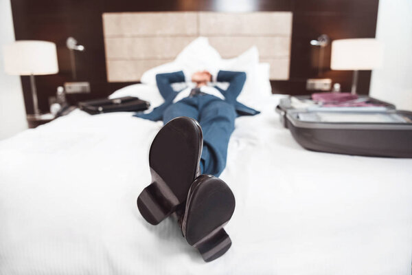 Exhausted businessman lying on bed