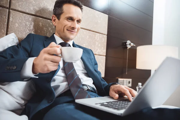 Hombre de negocios en la cama con ordenador portátil y café — Foto de Stock