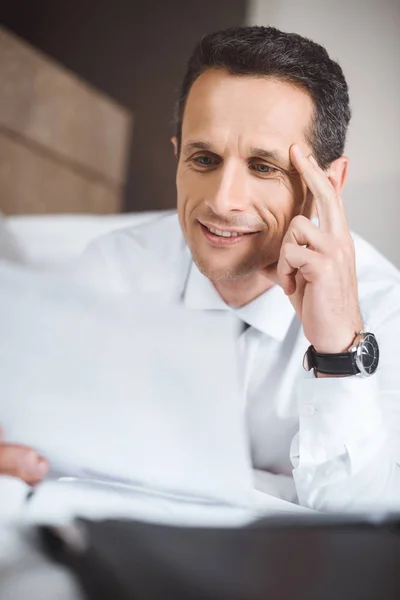 Businessman on bed reading paperwork — Stock Photo, Image