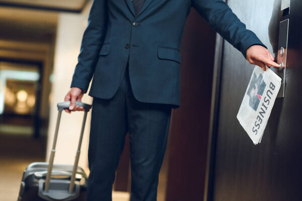 businessman with suitcase calling elevator