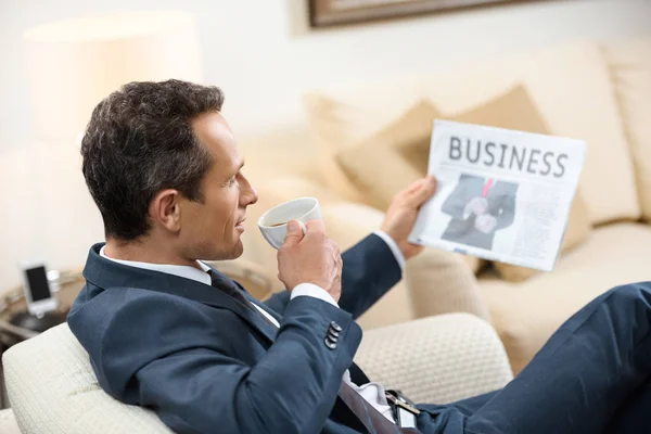 Businessman reading newspaper and drinking coffee — Stock Photo, Image