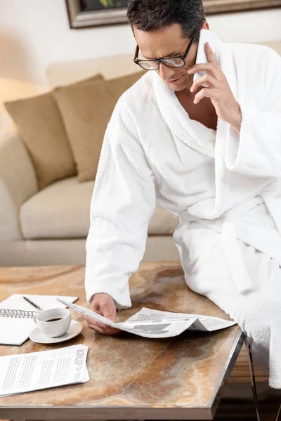 Businessman in bathrobe reading newspaper — Stock Photo, Image