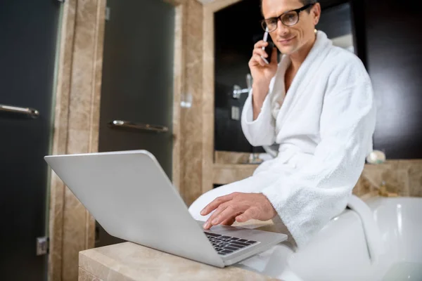 Empresário em roupão de banho usando laptop — Fotografia de Stock