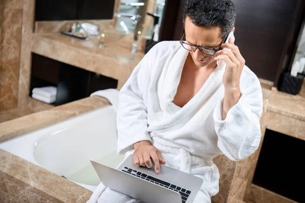 Geschäftsmann im Bademantel arbeitet mit Geräten — Stockfoto