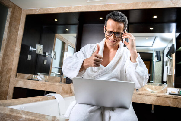 Businessman in bathrobe working with devices