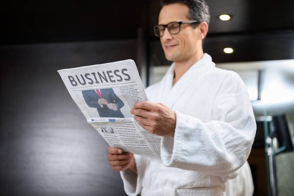 Businessman in bathrobe reading newspaper