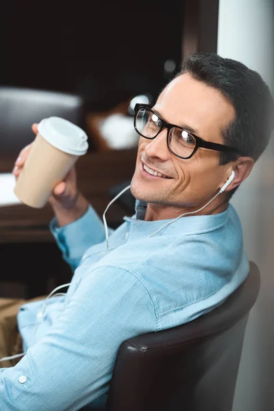 Businessman in headphones with coffee cup — Stock Photo, Image