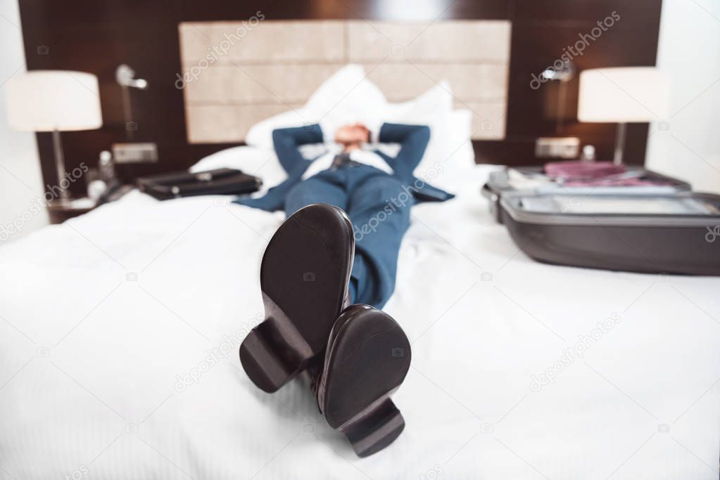 Exhausted businessman lying on bed