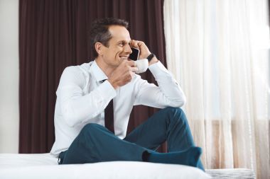 Yatakta kahve ve telefon ile işadamı
