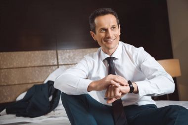 Yatağın üstüne oturan işadamı