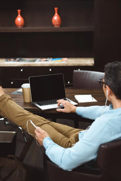 Businessman in headphones using laptop — Free Stock Photo