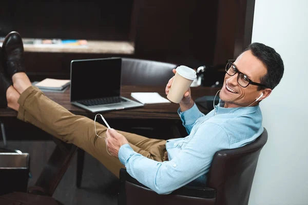 Businessman in headphones with coffee cup — Stock Photo, Image