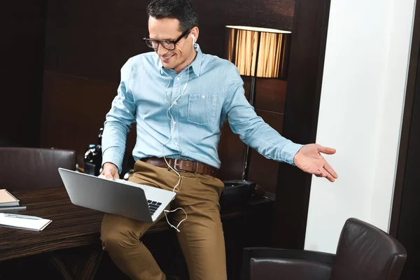 Homem de negócios rindo em fones de ouvido usando laptop — Fotografia de Stock