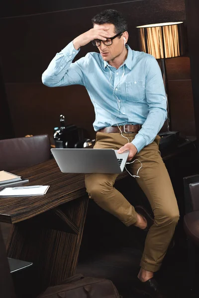 Homem de negócios rindo em fones de ouvido usando laptop — Fotografia de Stock Grátis