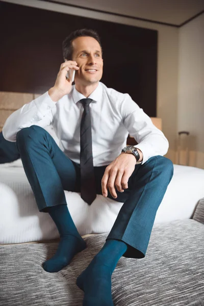 Businessman on bed talking on phone — Stock Photo, Image