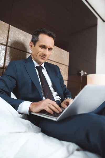 Businessman on bed using laptop — Free Stock Photo