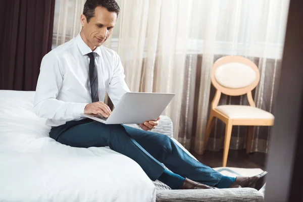 Бизнесмен на кровати с помощью ноутбука — Бесплатное стоковое фото