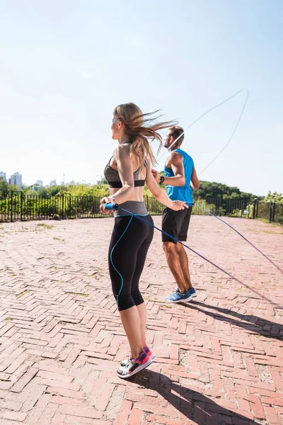 Sports couple jumping on skipping ropes — Stock Photo, Image