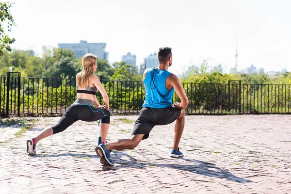 Sports couple doing lunge stretch — Stock Photo, Image