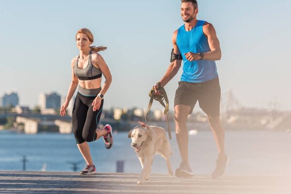 sportswoman and sportsman jogging with dog