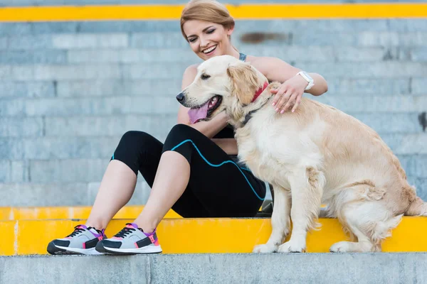 Idrottskvinna sitter med hund — Stockfoto
