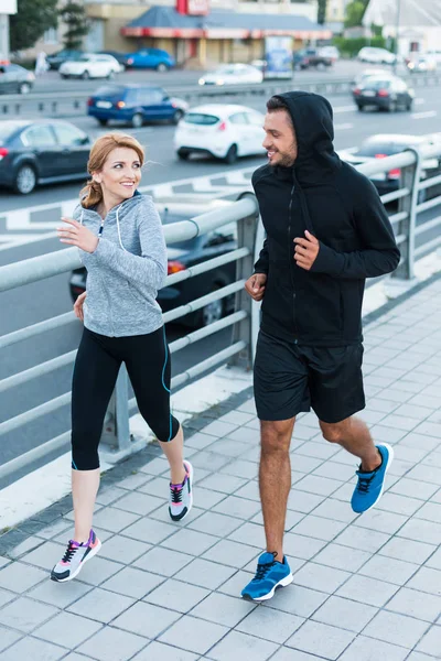 Deportiva y deportista trotando en la ciudad — Foto de Stock