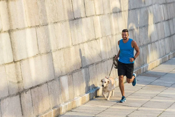 Sportsman running with dog — Stock Photo, Image