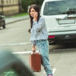Girl in roller skates with smartphone and suitcase