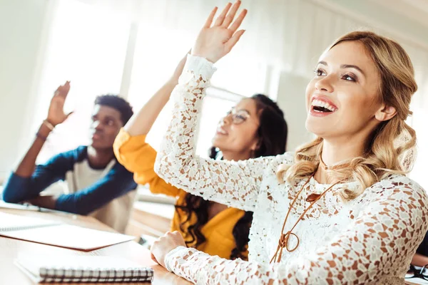 Students raising hands in class — Stock Photo, Image