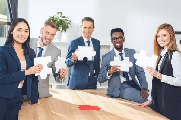 Businesspeople holding puzzle pieces — Stock Photo, Image