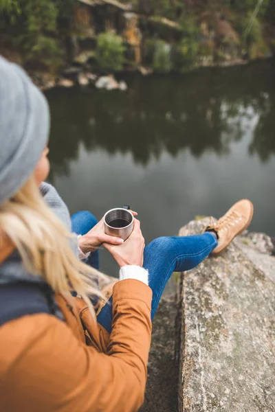 Mujer con taza de té sentado en la roca — Foto de Stock