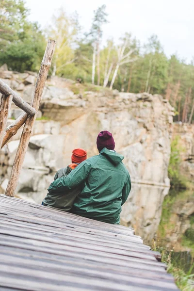 Father and son sitting on wooden bridge — Free Stock Photo