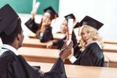 Multiethnische Studenten zeigen Diplome