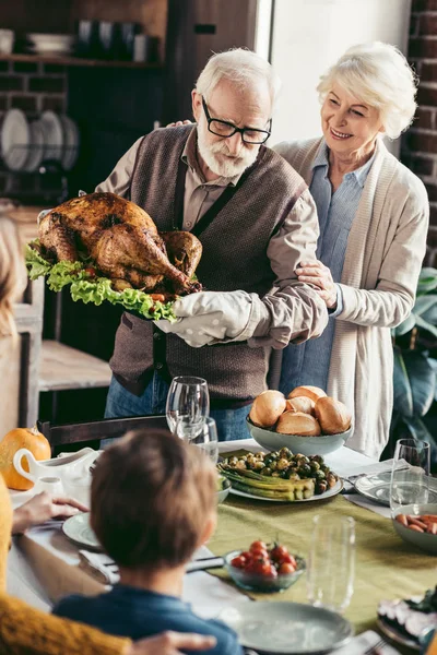 Abuelo poniendo pavo en la mesa de acción de gracias — Foto de Stock