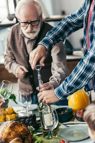 Hombres mayores y jóvenes abriendo vino — Foto de Stock