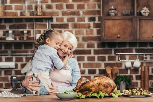 Бабуся і онука обіймаються на кухні — стокове фото
