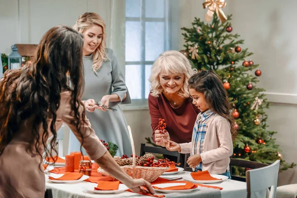 Γυναίκες που διακοσμεί χριστουγεννιάτικο τραπέζι με κορίτσι — Φωτογραφία Αρχείου