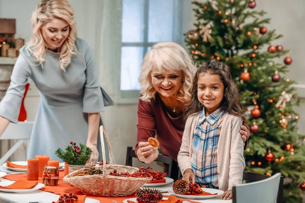 Women decorating christmas table with girl — Free Stock Photo