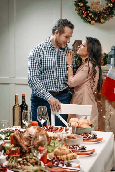 Casal abraçando ao lado da mesa de Natal — Fotografia de Stock