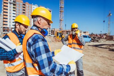 Construction worker examining building plan clipart