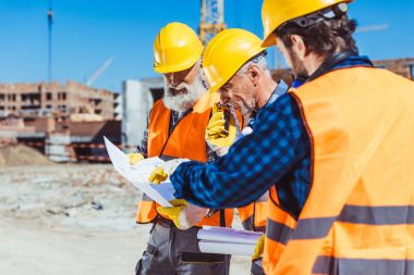 Bina planları tartışırken inşaat işçileri