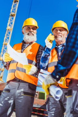 Construction workers discussing building plans clipart