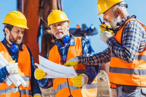 Byggnadsarbetare att undersöka byggplaner — Stockfoto