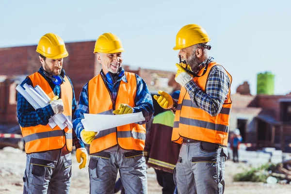 Trabajadores que examinan planes de construcción — Foto de Stock