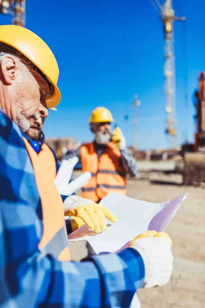 Byggande arbetare undersökande byggnadsplan — Stockfoto