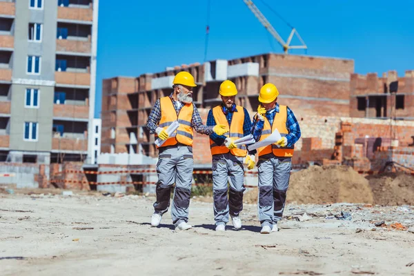 Tres trabajadores con sombreros en el sitio de construcción — Foto de Stock