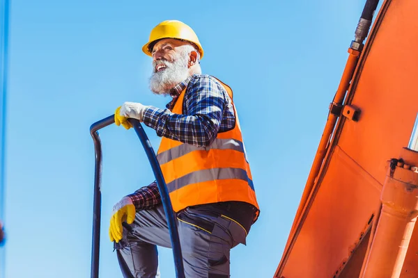 Byggnadsarbetare ovanpå grävmaskin stuga — Stockfoto